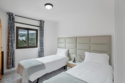 Un dormitorio con dos camas y una ventana. en El Granero, en Moya