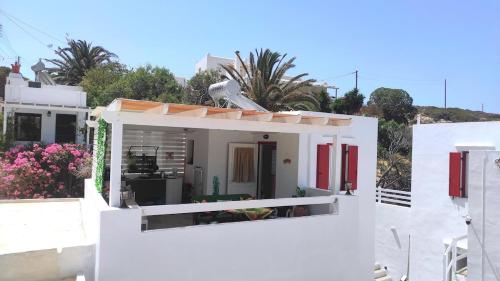 a white house with red doors and a balcony at Faros Sea View Studio - Sifnos in Faros