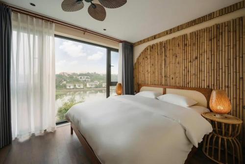 ein Schlafzimmer mit einem großen Bett und einem großen Fenster in der Unterkunft Hillstay Villa Resort in Ðông Sương