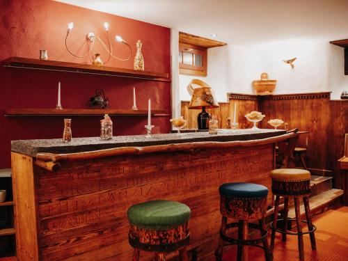 a bar in a room with stools at Parkhotel Schoenegg in Grindelwald