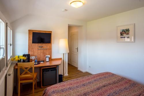 a bedroom with a bed and a desk with a computer at Insel-Hof Reichenau Hotel-garni in Reichenau