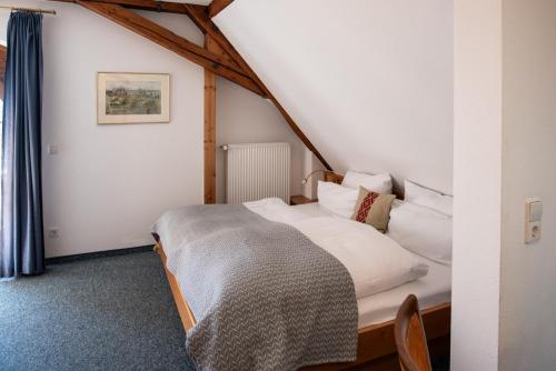 a bedroom with a bed with white sheets and pillows at Insel-Hof Reichenau Hotel-garni in Reichenau