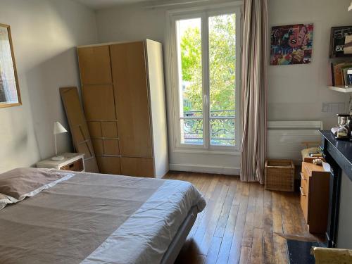 une chambre avec un lit et une grande fenêtre dans l'établissement Hotel particulier Montrouge -limitrophe Paris, à Montrouge