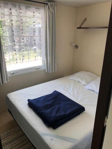 - un lit avec une serviette bleue dans une chambre dans l'établissement Domaine des Iscles mobile home clim, jardinet sans vis-à-vis, à La Roque-dʼAnthéron