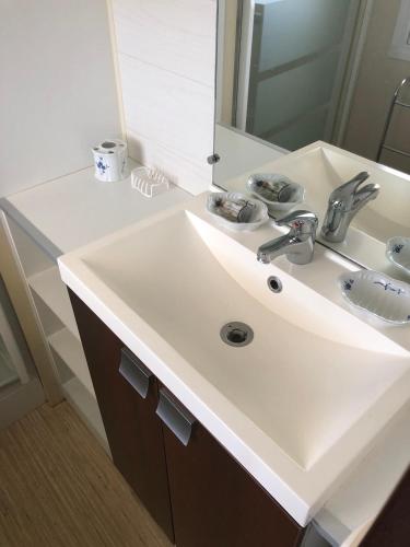 une salle de bain avec un lavabo blanc et un miroir dans l'établissement Domaine des Iscles mobile home clim, jardinet sans vis-à-vis, à La Roque-dʼAnthéron