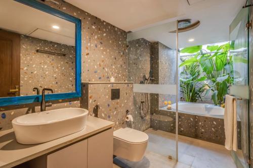 a bathroom with a sink and a tub and a toilet at Casa da Paz by Hireavilla - Luxe 4BHK Villa near Morjim Beach in Morjim