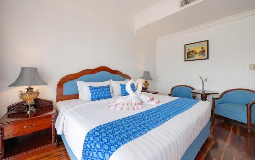 a bedroom with a bed with two blue chairs at Hotel Somadevi Angkor Resort & Spa in Siem Reap