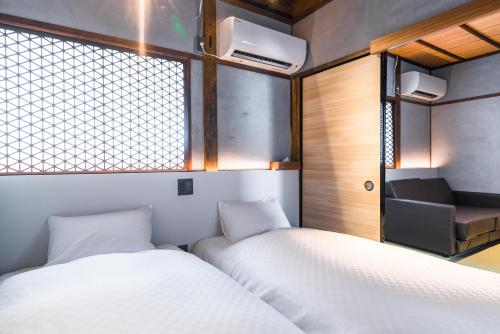 two beds in a small room with a window at KONJAKUSO Osaka Bentencho "HIKARIYUYA" Projection M apping SPA in Osaka