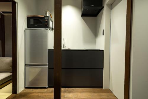 a small kitchen with a refrigerator and a microwave at KONJAKUSO Osaka Bentencho "HIKARIYUYA" Projection M apping SPA in Osaka