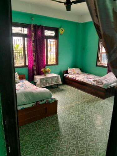 Dos camas en una habitación con paredes y ventanas verdes. en New aamos guest house and khaja ghar, en Rāmechhāp