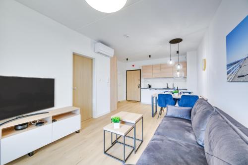 a living room with a gray couch and a tv at ReVital Mechelinki by Homeprime Parking Free in Mechelinki