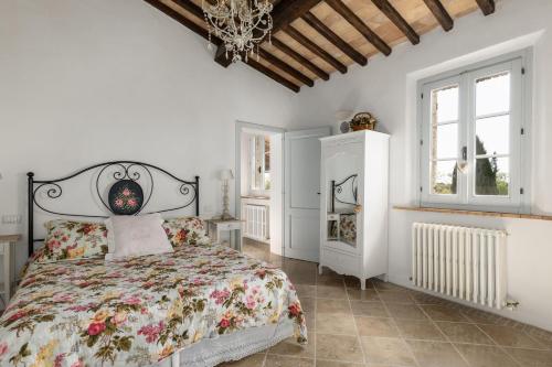 a white bedroom with a bed with a floral bedspread at Casale delle Mele by PosarelliVillas in I Pieracci
