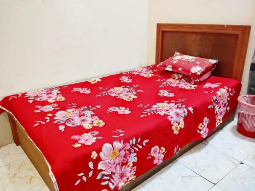 a bed with a red blanket with flowers on it at Hotel Garden View Jatrabari in Dhaka