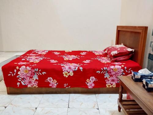 a bed with a red blanket with flowers on it at Hotel Garden View Jatrabari in Dhaka
