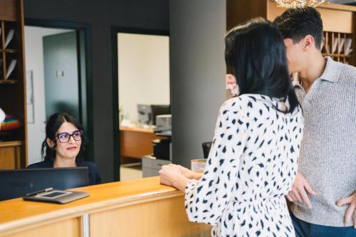 two people standing at a counter in an office at Sardegna Termale Hotel&SPA in Sardara