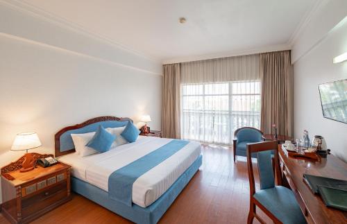 a hotel room with a bed and a desk and a desk at Hotel Somadevi Angkor Resort & Spa in Siem Reap