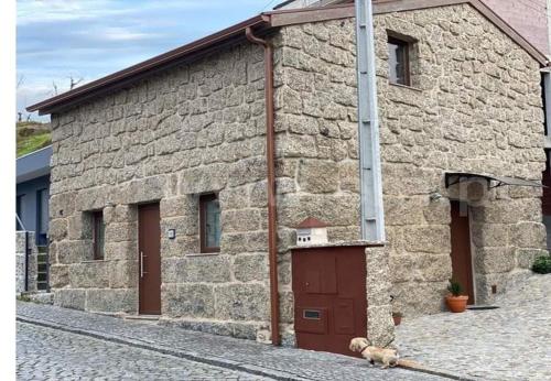 a stone building with a dog sitting in front of it at Costa Guest House in Guimarães