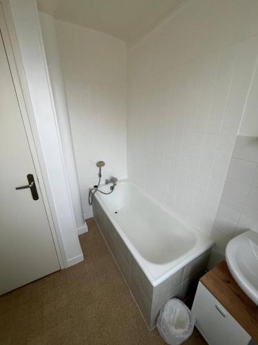 une salle de bain blanche avec une baignoire et un lavabo dans l'établissement Le Marceau, à Colombes