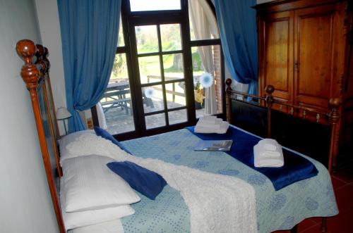 a bedroom with a bed with blue curtains and a window at Agriturismo il Pino - Bioagricoltura in Monticello