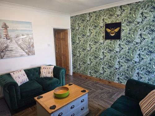 a living room with a green couch and a table at Eden Rose Cottage hot-tub jacuzzi morecambe-bay in Morecambe