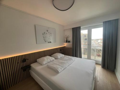 een slaapkamer met een wit bed en een groot raam bij Beach Suite Leonie Koksijde met zeezicht in Koksijde