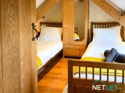 two twin beds in a room with wooden walls at Ty Eithin - Rustic Cottage in St Davids in St. Davids