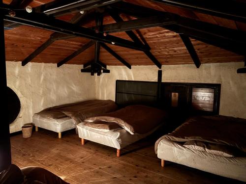 two beds in a room with wooden ceilings at HiddenVilla in Nakijin