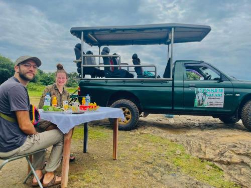 a man and woman sitting at a table in front of a truck at Udawalawa Eco Lodge in Udawalawe