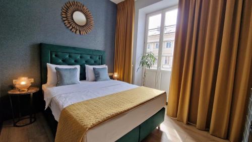 a bedroom with a bed with a green headboard and a window at SLEEPWELL NOWY ŚWIAT - wejście przez dziedziniec - brama Ordynacka 14 in Warsaw