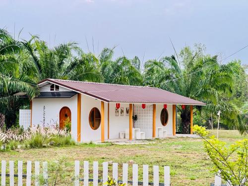 a small house with a white fence in front of it at สวนปาล์มการ์เด้นโฮม เชียงคาน Suanpalm Garden Home Changkhan in Chiang Khan