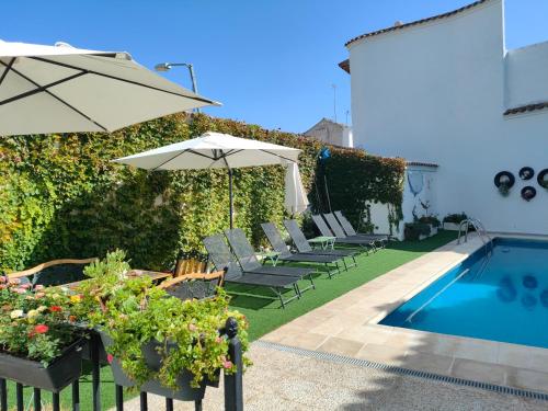 a backyard with a pool and chairs and an umbrella at Casa Capricho del Destino in Villatobas