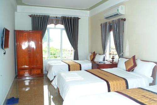 a hotel room with three beds and a window at Paradise Hotel in Phong Nha