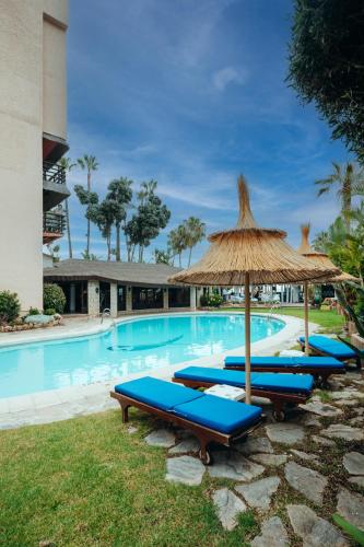 a swimming pool with blue lounge chairs and an umbrella at Hotel MS Tropicana Costa del Sol in Torremolinos