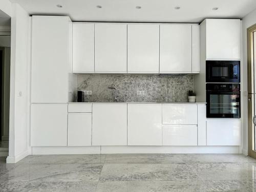 - une cuisine blanche avec des armoires blanches et des appareils noirs dans l'établissement Cannes Centre Mimosas 1 chambre Salon, à Cannes
