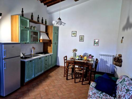 a kitchen with green cabinets and a table with a dining room at Agriturismo il Pino - Bioagricoltura in Monticello