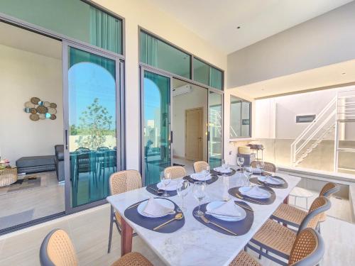 a dining room with a table and chairs and windows at ภัทรา พูลวิลล่า ชะอำ Phattra Poolvilla Cha-am in Cha Am