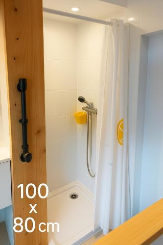 La salle de bains est pourvue d'une douche avec un rideau de douche blanc. dans l'établissement La Cure Marine Wifi Terrasse, à Rochefort