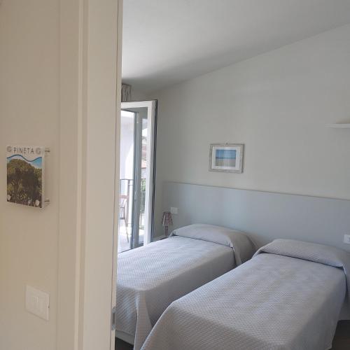 two beds in a room with white walls at Slowersilia Bed and Breakfast in Lido di Camaiore