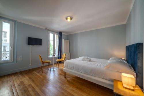 - une chambre avec un lit, deux chaises et une télévision dans l'établissement Majestic Suite, à Paris