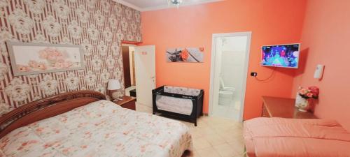 a bedroom with orange walls and a bed and a tv at B&B JOY in Nettuno
