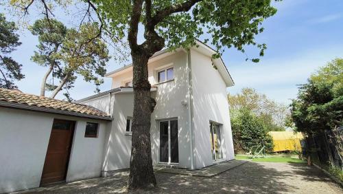 une maison blanche avec un arbre devant dans l'établissement Les Fougères maison tout confort 4 personnes, à Andernos-les-Bains