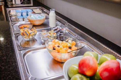 a sink with bowls of fruit and a plate of apples at Hotel Corsendonk Viane in Turnhout