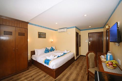 a bedroom with a bed and a desk and a television at Tibet Boutique Hotel in Kathmandu