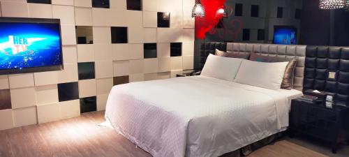 a bedroom with a white bed and a tv at Icloud Luxury Resort & Hotel in Taichung