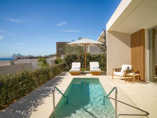 a swimming pool with two chairs and an umbrella at Fairmont La Hacienda Costa del Sol in Alcaidesa