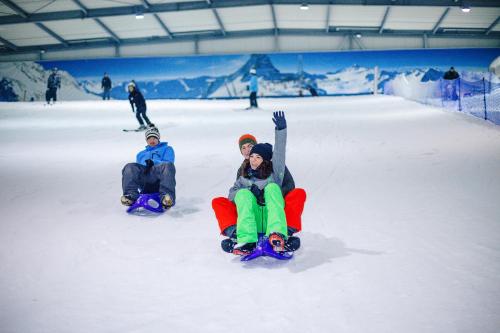 two people are sitting in the snow on snowboards at Alpine Hotel in Bispingen