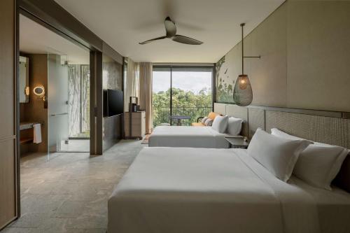 a hotel room with two beds and a television at Mandai Rainforest Resort by Banyan Tree in Singapore