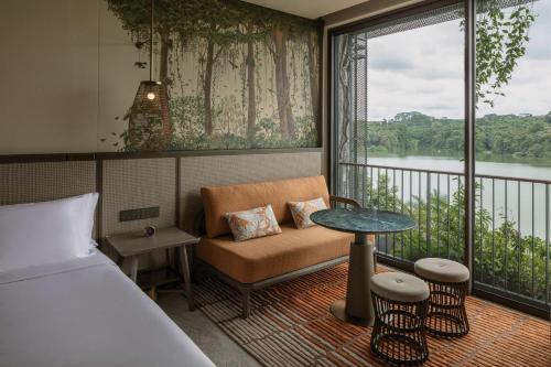 a room with a bed and a table and a window at Mandai Rainforest Resort by Banyan Tree in Singapore
