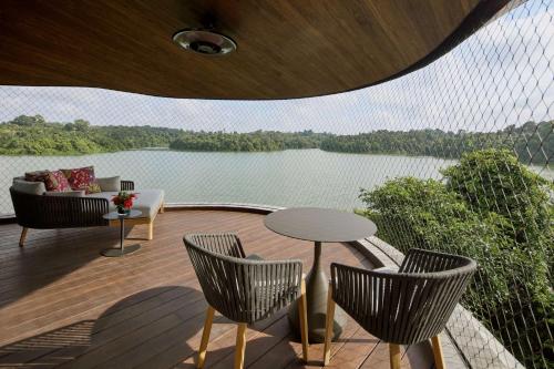 a deck with chairs and a table and a view of a lake at Mandai Rainforest Resort by Banyan Tree in Singapore