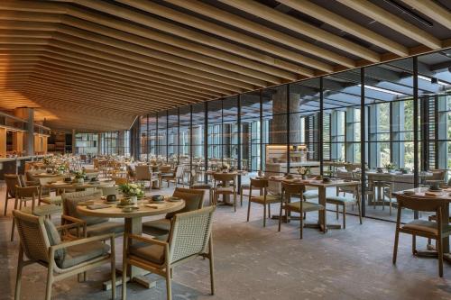 a dining room with tables and chairs and windows at Mandai Rainforest Resort by Banyan Tree in Singapore